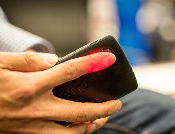 Imagen: La HemaApp mide los niveles de hemoglobina mediante la iluminación de un dedo con el flash de la cámara de un teléfono inteligente (Fotografía cortesía de Dennis Wise/UW).