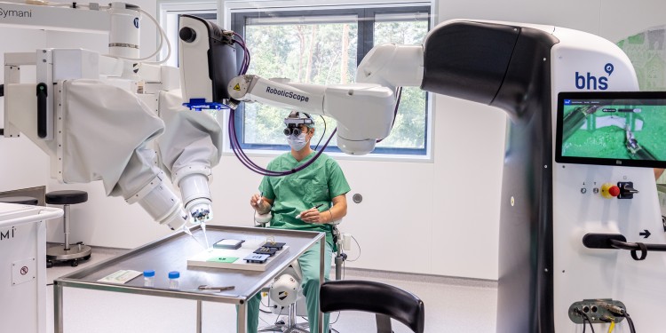 Imagen: El robot de operaciones (derecha) está conectado en red con un microscopio robótico (izquierda) (Fotografía cortesía de la Universidad de Münster)