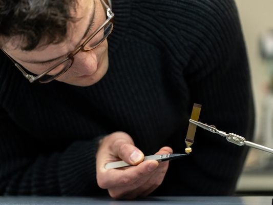 Imagen: Jonathan ’’Jono’’ Pelusi, becario de innovación de doctorado, examina el dispositivo neuronal diseñado para promover la curación del cráneo tras su implantación en el cerebro (Foto cortesía de Robert Anderson)