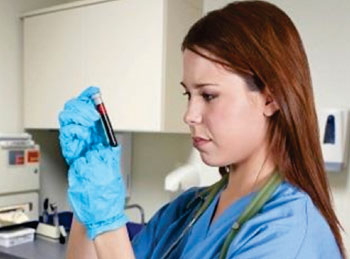 Imagen A: Un flebotomista examinando una muestra de sangre para ser utilizada para múltiples pruebas ordenadas por el médico (Fotografía cortesía del Centro Medico de la Universidad de Utah).