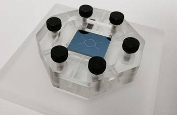 Imagen: El chip nano-DLD (2 cm x 2 cm) montado en una plantilla de microfluidos. La tecnología permite que una muestra líquida pase, en flujo continuo, a través de un chip de silicio que contiene una matriz de pilares asimétrica que clasifica una cascada microscópica de las nanopartículas, separando partículas por tamaño hasta una resolución de 20 nanómetros (Fotografía cortesía de IBM Investigación).