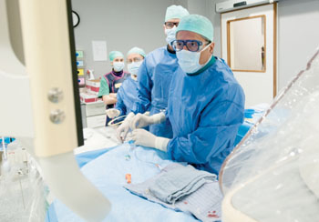 Imagen A: El Prof. Maleux, radiólogo intervencionista del Hospital Universitario de Lovaina (Bélgica) y su equipo mientras realizan un procedimiento de embolización (Fotografía cortesía de Philips Healthcare).