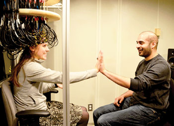 Image: Research participants Britt Gott (left) and Sridhar Kandala demonstrate the ability to interact while being scanned via diffuse optical tomography. Patients in MRI scanners do not have the same freedom to move and interact (Photo courtesy of Washington University School of Medicine in St. Louis).
