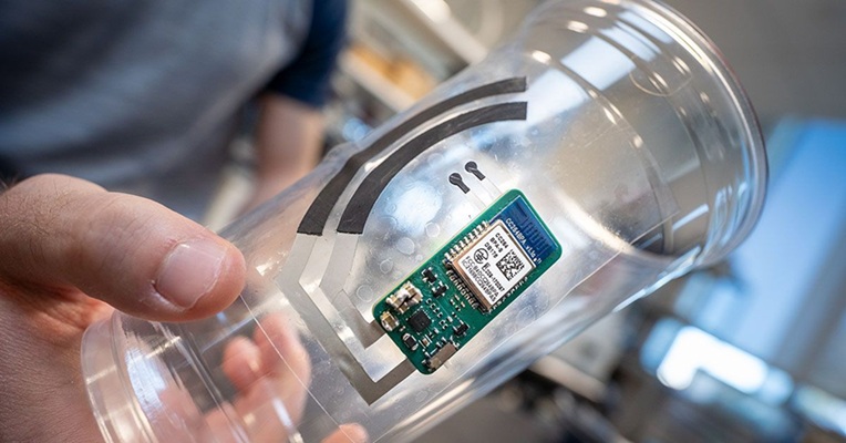 Image: The electronic sticker attaches to a drinking cup and monitors vitamin C levels from fingertip sweat (Photo courtesy of David Baillot/UC San Diego Jacobs School of Engineering)