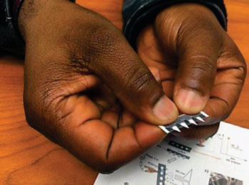Image: A chemist holds a prototype test strip for diagnosing diseases including cancer and malaria (Photo courtesy of Pam Frost Gorder).