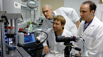 Image: From left, Guy Genin, PhD, John Boyle and Stavros Thomopoulos, PhD, watch as a sample is exposed to stress and force. They have developed algorithms that may lead to the ability to identify weak spots in tendons, muscles and bones (Photo courtesy of Washington University in St. Louis).