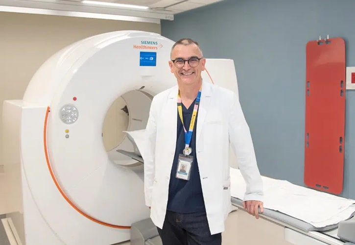 Imagen: el Dr. Glenn Bauman, científico de LHSCRI, posa frente al escáner PET (Foto cortesía de LHSCRI).