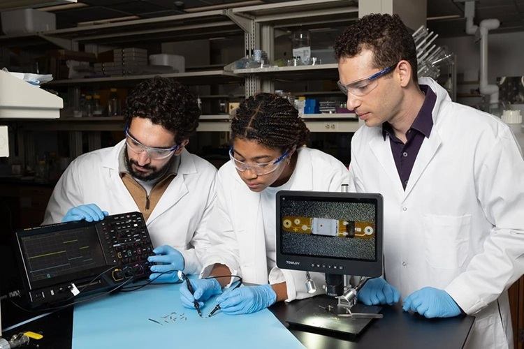 Image: Lead study author Ramy Ghanim (left) and co-author Joy Jackson test an small implantable device alongside Assistant Professor Alex Abramson. In a new Science paper, they describe a networking system that connects therapeutic implants and wearable devices by using the body’s natural conductivity to send tiny signals. (Photo courtest of Georgia Tech)
