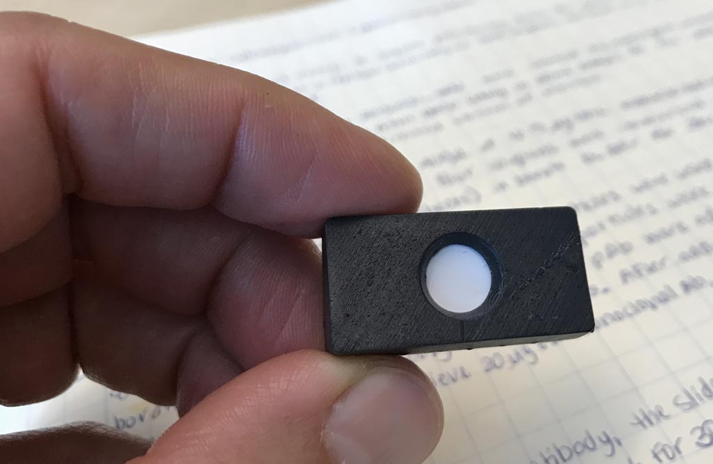 Image: A small domino-sized cartridge holds the membrane for the newly developed low-cost field test for liver cancer screening (Photo courtesy of the University of Utah College of Engineering).